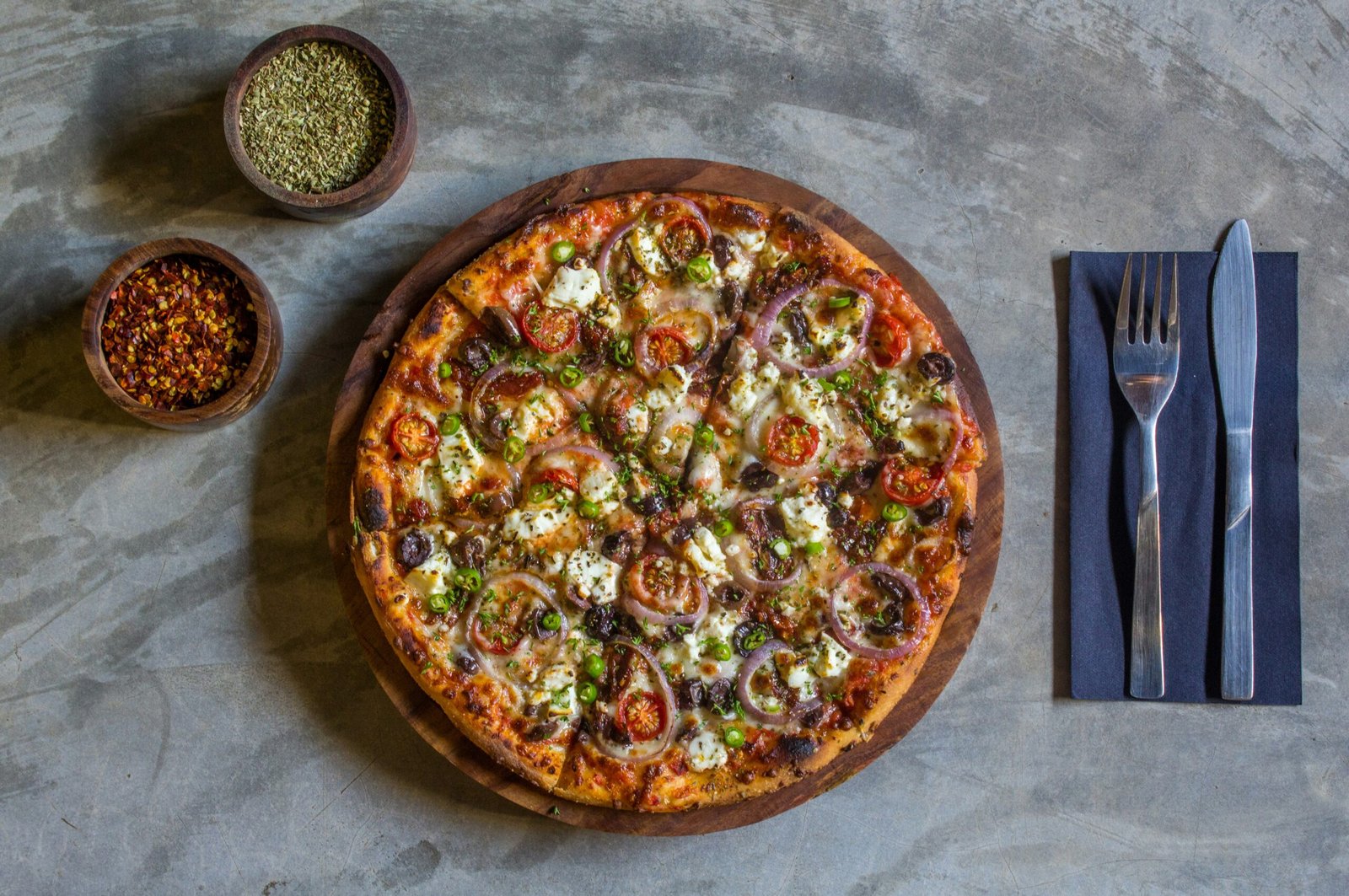 A pizza sitting on top of a table next to a fork and knife